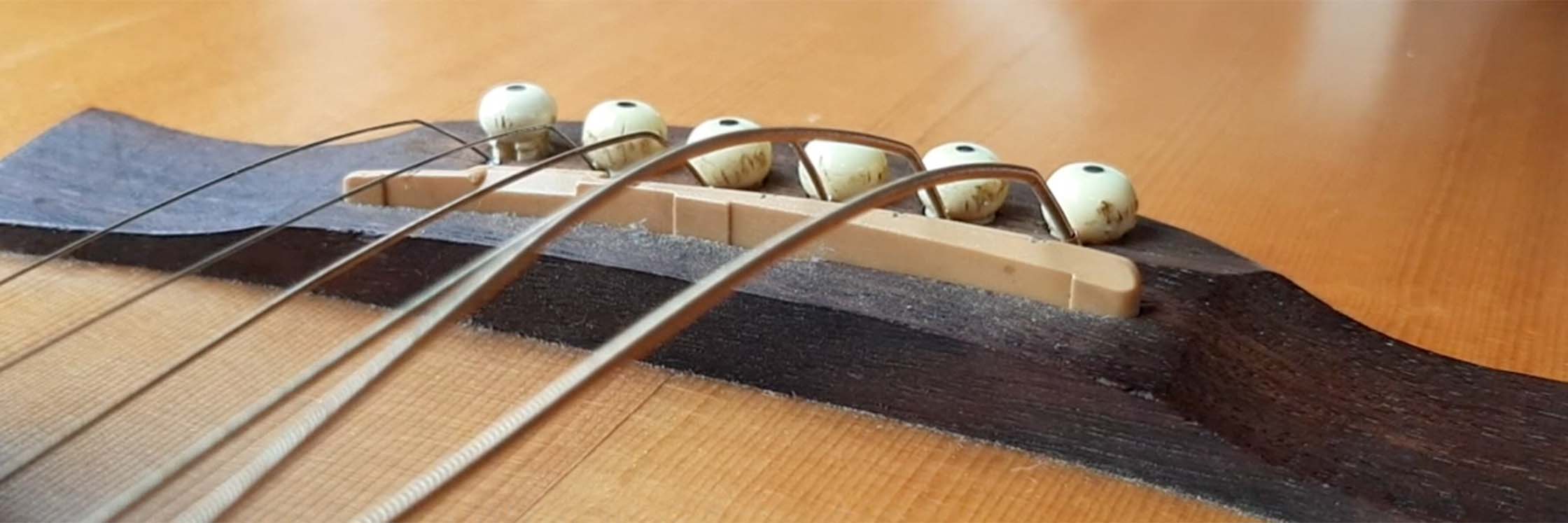 Guitar action adjustment – strings over the saddle on an acoustic guitar bridge