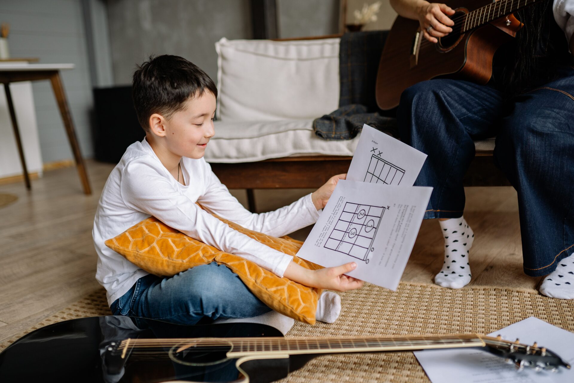 Young person practising guitar with chord sheets