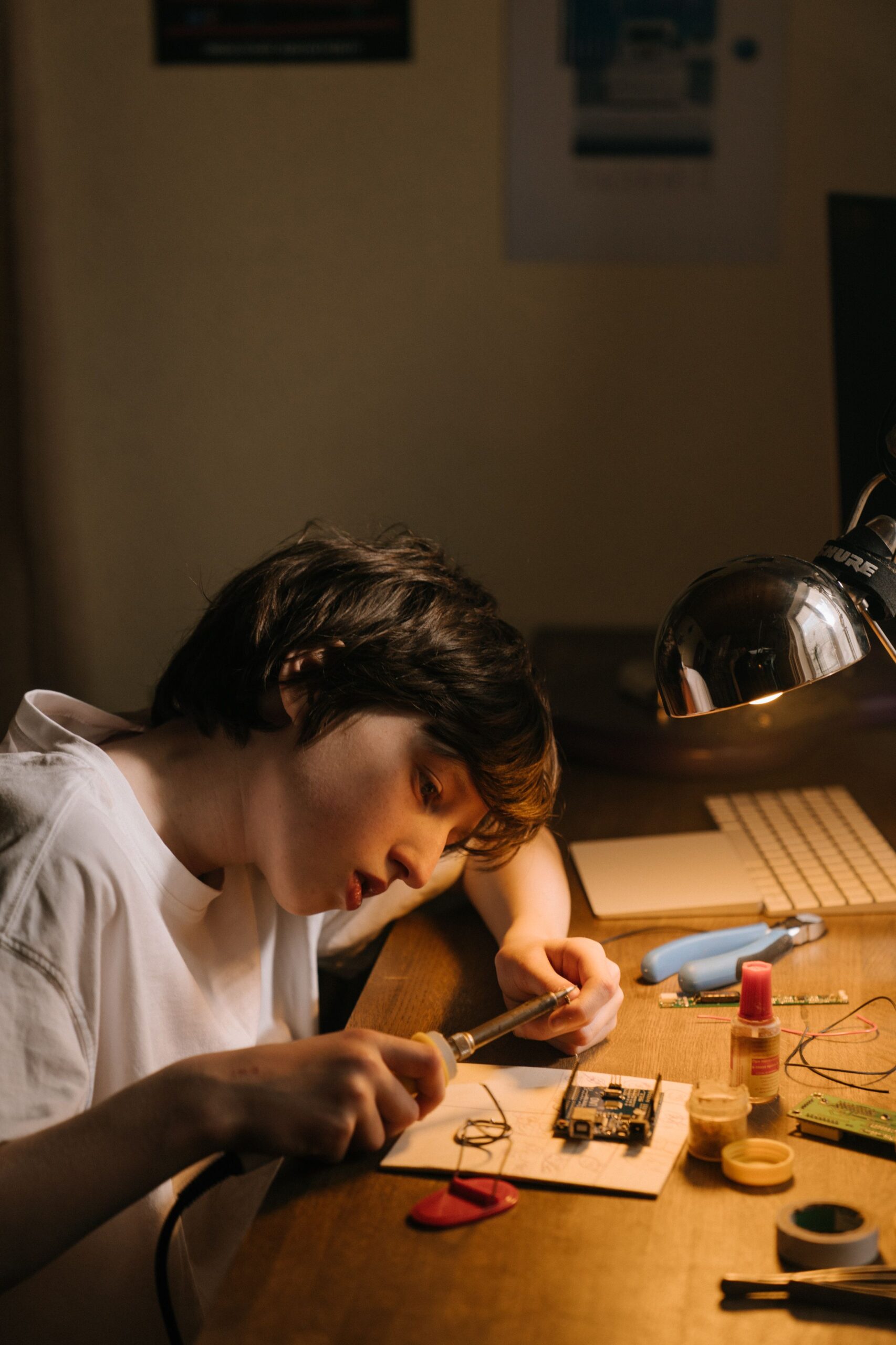 Young person soldering an electronics circuit board