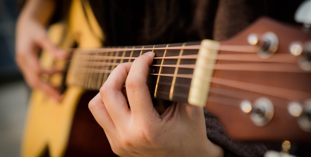 Close-up of fingers on acoustic guitar strings