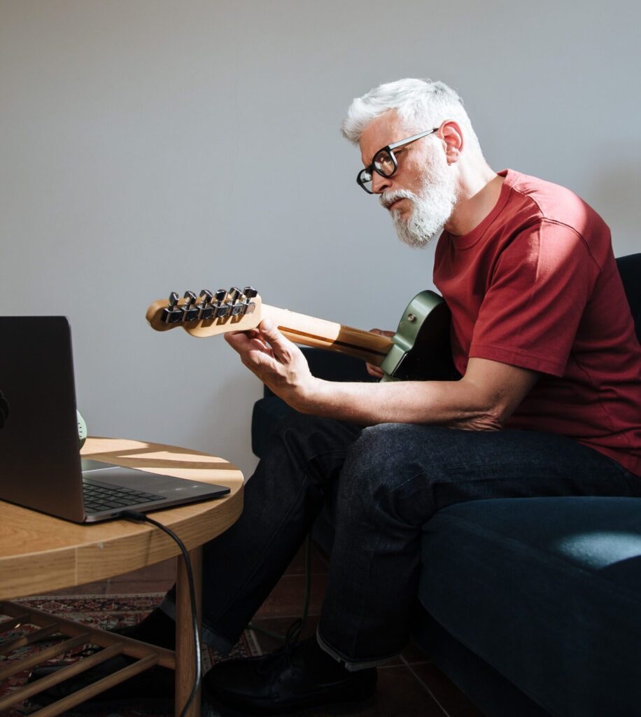 Older man playing an electric guitar at home